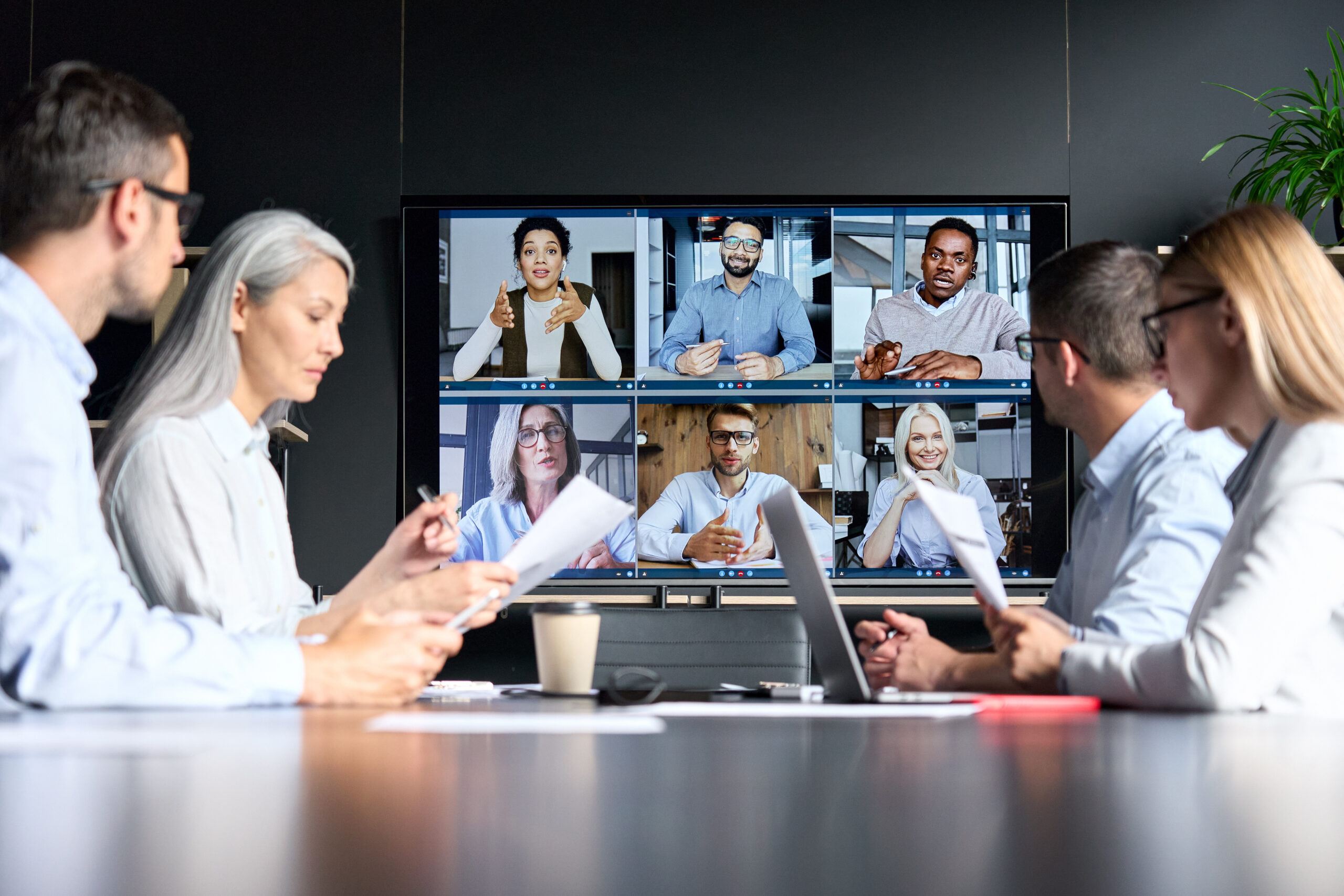 Global corporate video call in meeting room with diverse multiethnic people. hybrid-meeting-room